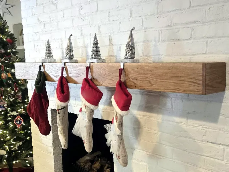 Real wood floating mantel on a white brick fireplace with holiday stockings