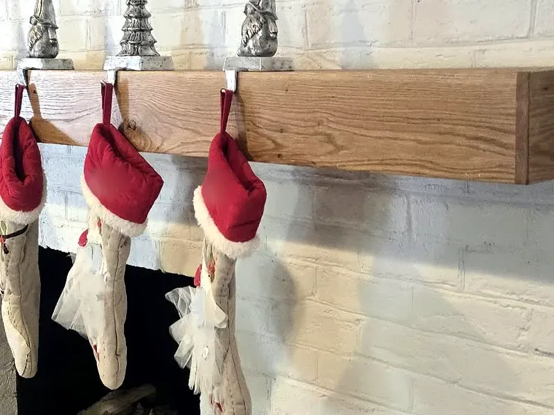 Real wood floating mantel with holiday stockings on a white brick fireplace