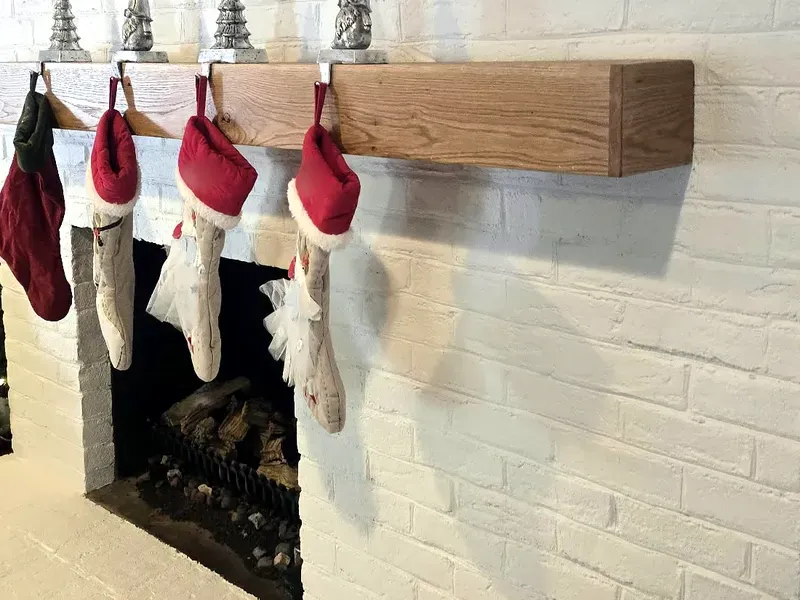 Real wood floating mantel above a painted brick fireplace opening
