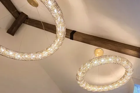 Dark stained wood beam crossing a vaulted ceiling with crystal chandeliers