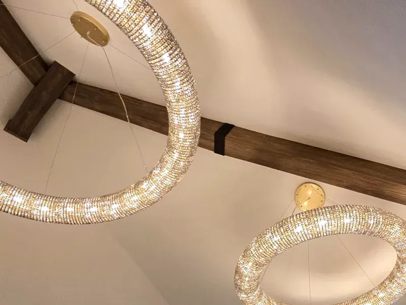 Dark stained real wood beam crossing a vaulted ceiling between two crystal chandeliers