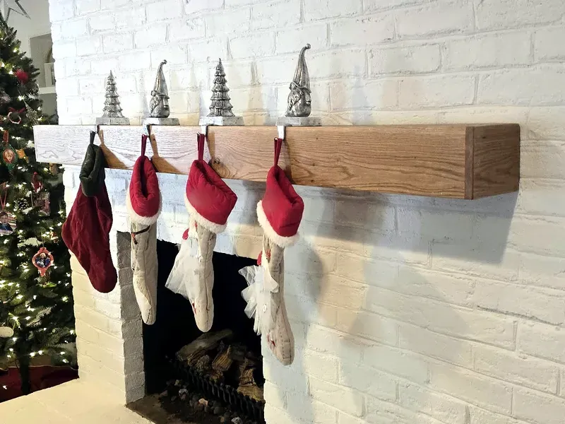 Real wood floating mantel on a painted white brick fireplace, built by Chava Grain & Beam by Chava Home Design