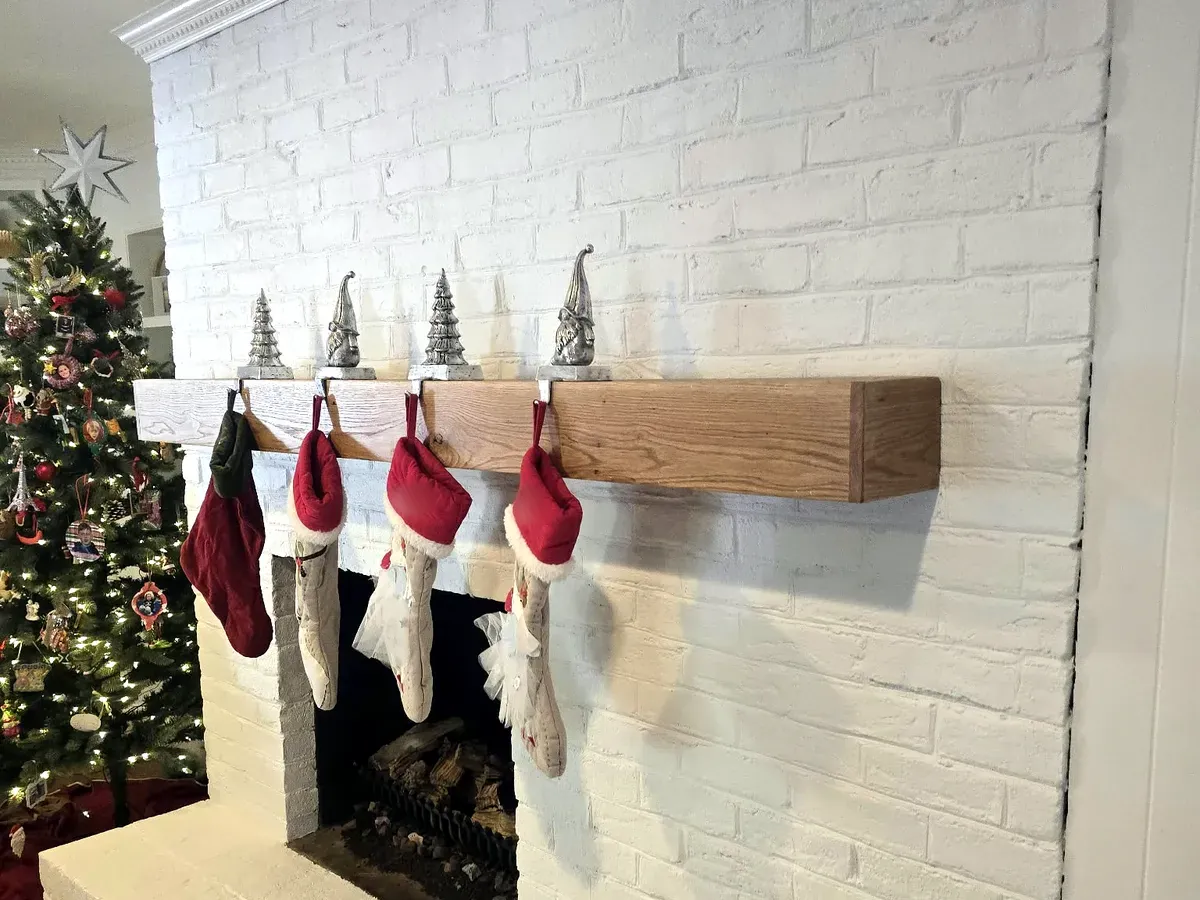 Real wood floating mantel on a painted white brick fireplace decorated for the holidays